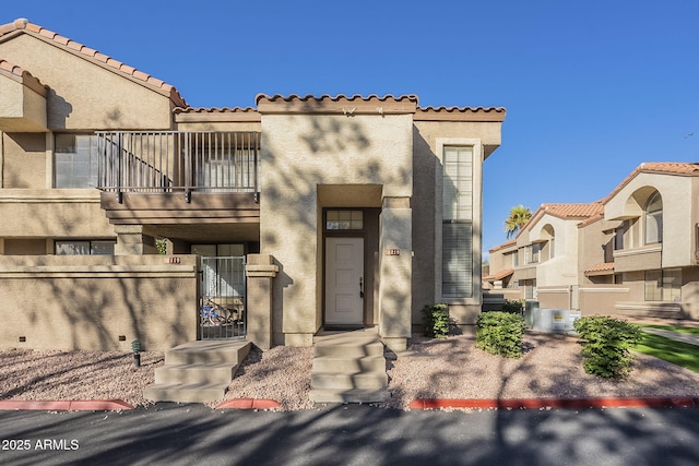 view of front facade featuring a gate, a tile roof, a balcony, and stucco siding