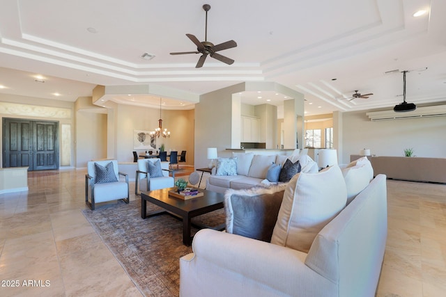 living room with ceiling fan with notable chandelier and a raised ceiling