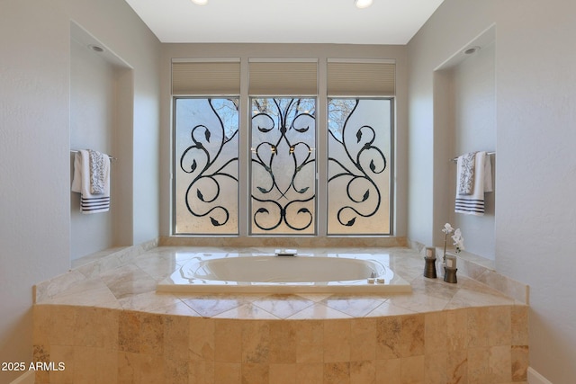 bathroom featuring a relaxing tiled tub and a wealth of natural light