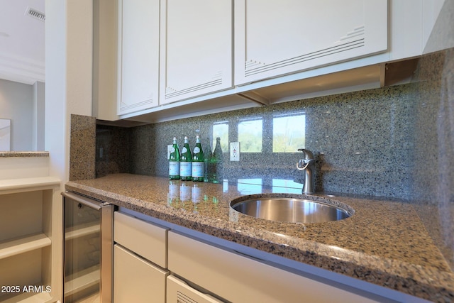 kitchen with white cabinetry, sink, beverage cooler, tasteful backsplash, and dark stone counters