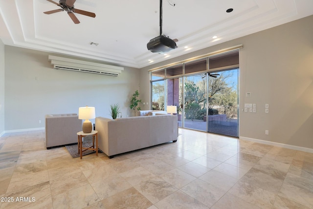 living room with a tray ceiling, a wall mounted AC, and ceiling fan