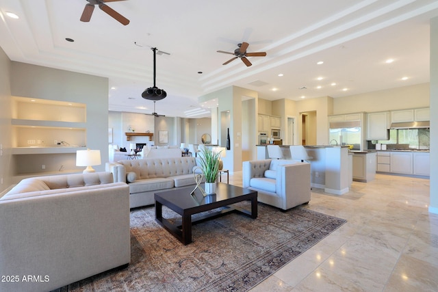 living room featuring a tray ceiling, ceiling fan, and built in features