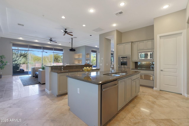 kitchen with stainless steel appliances, ceiling fan, a center island with sink, and sink