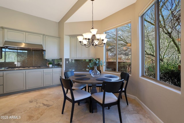 dining area featuring lofted ceiling, plenty of natural light, and a notable chandelier