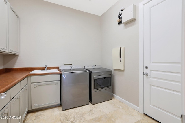 clothes washing area featuring washing machine and dryer, sink, light tile patterned flooring, and cabinets