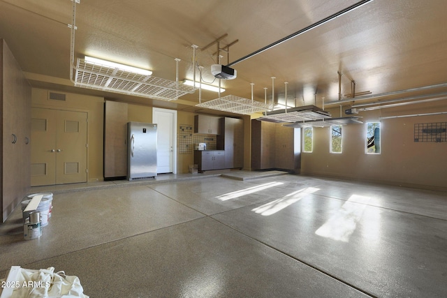 garage featuring stainless steel refrigerator and a garage door opener