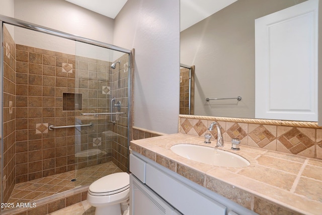 bathroom featuring vanity, tasteful backsplash, toilet, and a shower with shower door