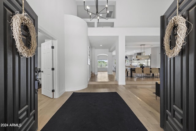 foyer entrance with a high ceiling, light hardwood / wood-style flooring, and a notable chandelier