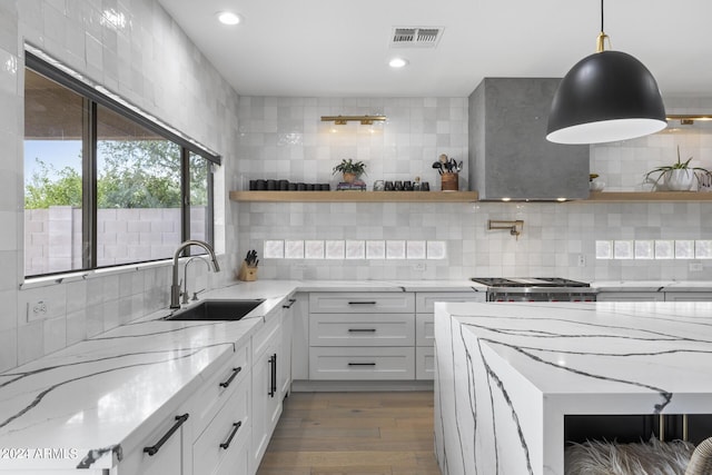 kitchen with sink, pendant lighting, white cabinets, and light stone counters