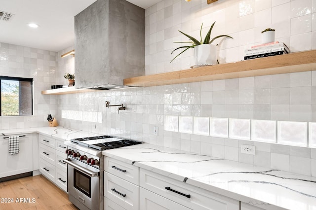 kitchen with ventilation hood, high end stainless steel range, and light stone counters