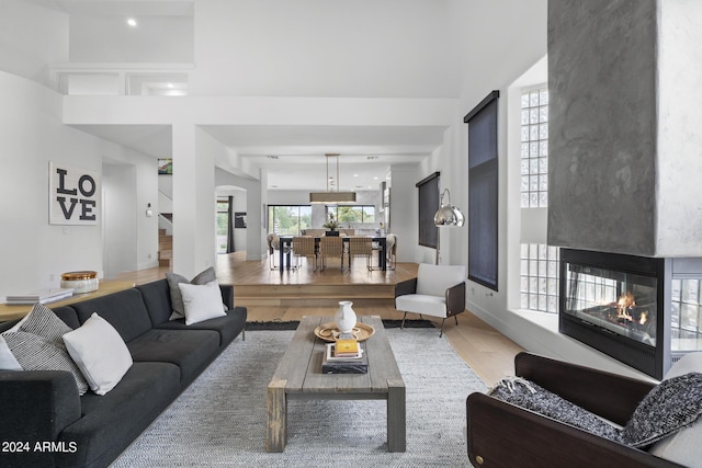 living room featuring hardwood / wood-style flooring, a multi sided fireplace, and a high ceiling