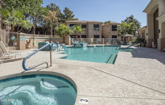 community pool featuring fence, a community hot tub, and a patio