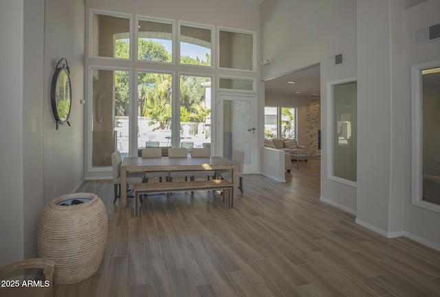 dining room featuring a high ceiling, visible vents, and wood finished floors