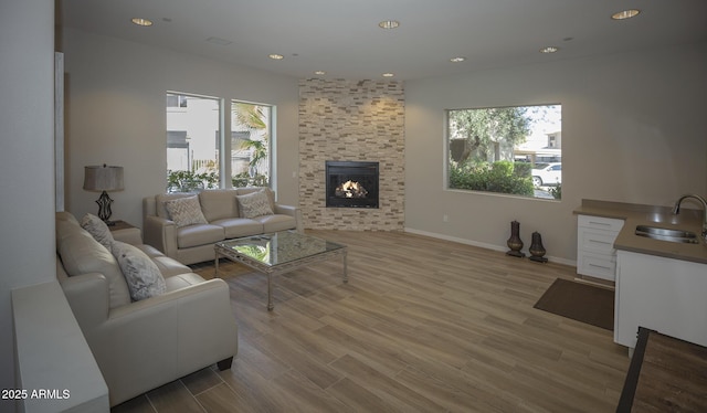 living room with a healthy amount of sunlight, light wood finished floors, a fireplace, and recessed lighting