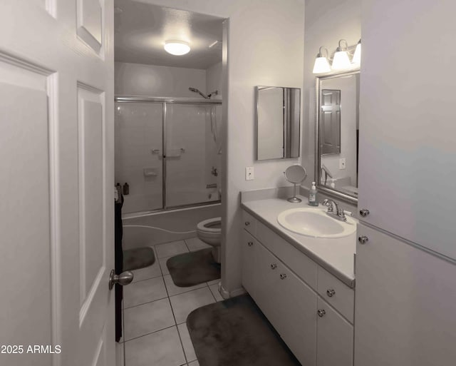 bathroom with vanity, combined bath / shower with glass door, tile patterned flooring, and toilet