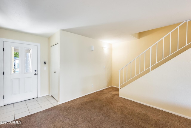 carpeted entryway featuring tile patterned floors, stairway, and baseboards