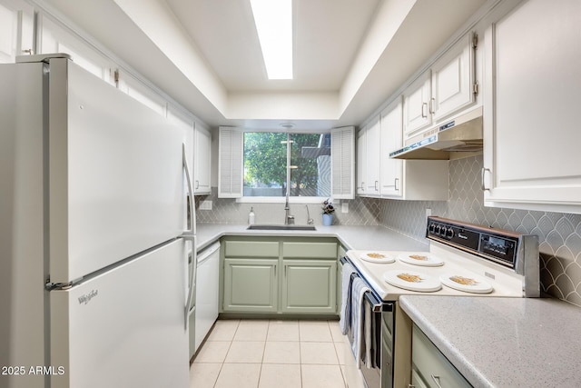 kitchen with backsplash, under cabinet range hood, light countertops, white appliances, and a sink