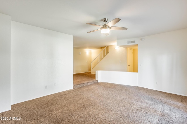 empty room with stairs, a ceiling fan, visible vents, and carpet floors