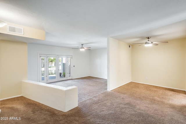 carpeted spare room with baseboards, visible vents, and ceiling fan