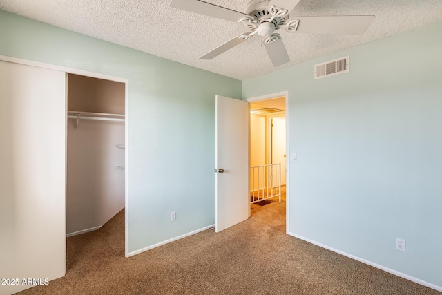 unfurnished bedroom featuring a closet, visible vents, a textured ceiling, and carpet floors