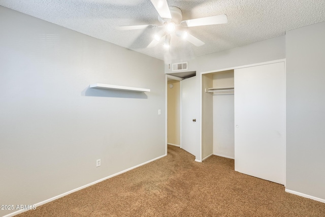 unfurnished bedroom featuring a closet, carpet floors, a textured ceiling, and visible vents