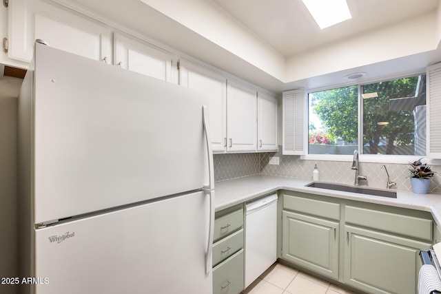 kitchen featuring backsplash, light countertops, white appliances, white cabinetry, and a sink