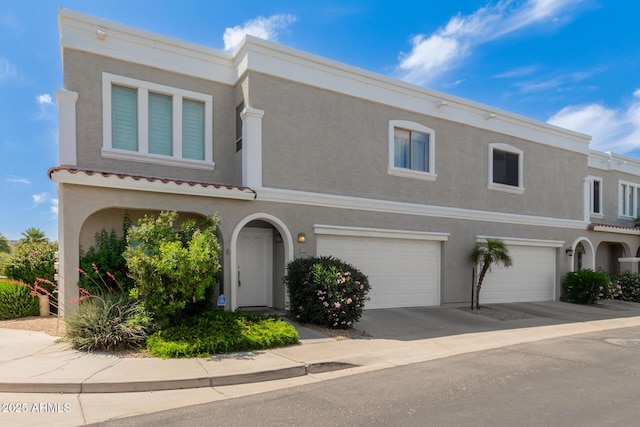 view of front of house featuring an attached garage, stucco siding, a tiled roof, and concrete driveway