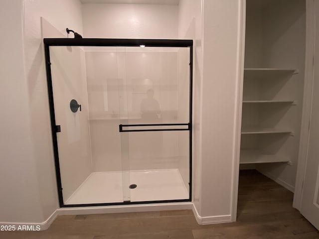 full bathroom with a shower stall, baseboards, and wood finished floors