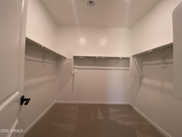 spacious closet with dark carpet and visible vents