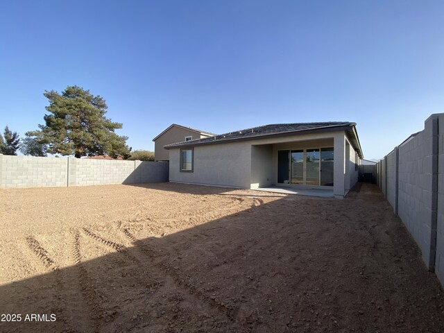 rear view of property with a fenced backyard and stucco siding