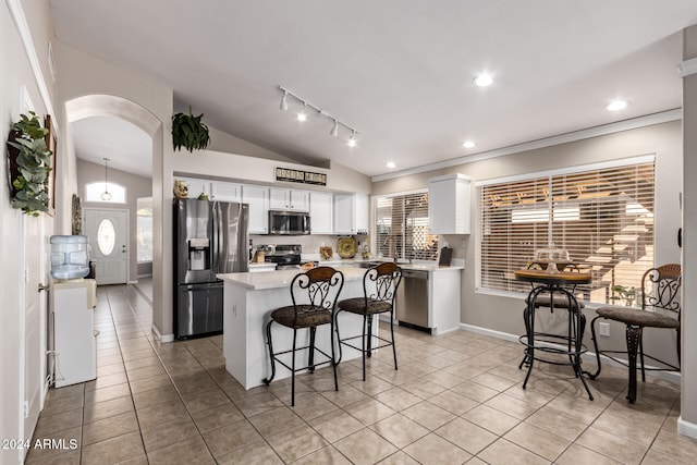 kitchen with white cabinetry, stainless steel appliances, a kitchen breakfast bar, vaulted ceiling, and a kitchen island