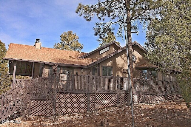 back of property with a shingled roof, stairway, a chimney, and a wooden deck