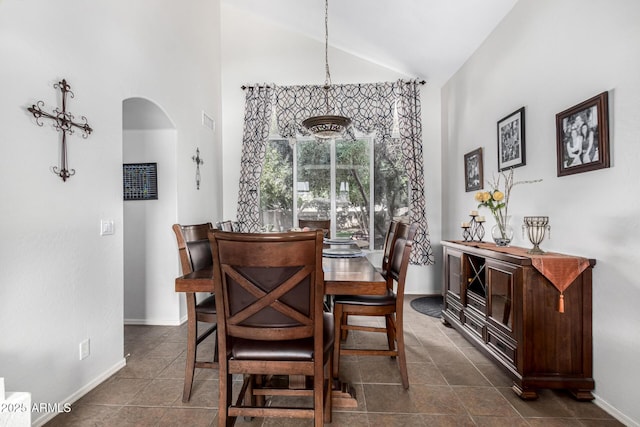 dining area featuring arched walkways, high vaulted ceiling, dark tile patterned floors, visible vents, and baseboards