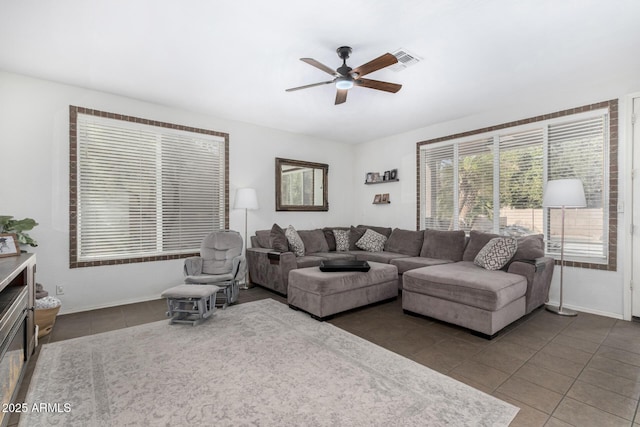 living area featuring tile patterned flooring, visible vents, ceiling fan, and baseboards