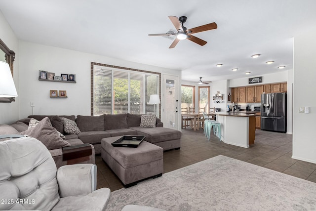 living area with dark tile patterned floors and a ceiling fan