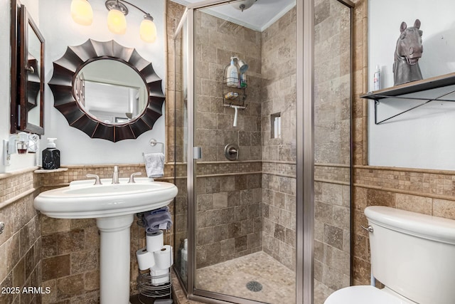 bathroom featuring a wainscoted wall, tile walls, and a shower stall