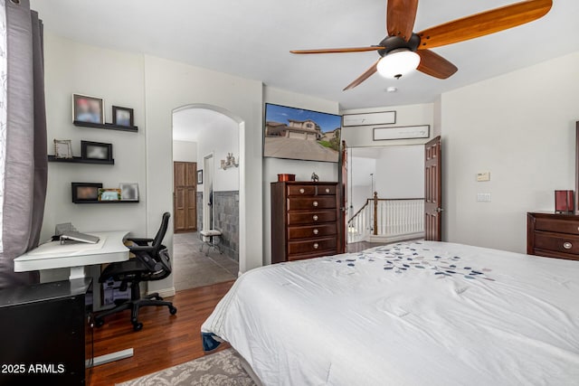 bedroom with ensuite bath, ceiling fan, arched walkways, and wood finished floors