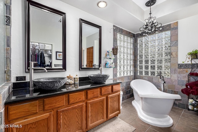 bathroom featuring double vanity, a soaking tub, a sink, tile patterned flooring, and tile walls