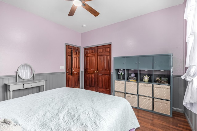 bedroom with a ceiling fan, a closet, a wainscoted wall, and wood finished floors