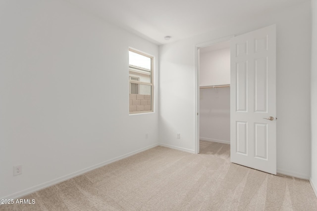 unfurnished bedroom featuring light colored carpet, a spacious closet, and a closet