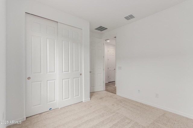 unfurnished bedroom with light colored carpet and a closet