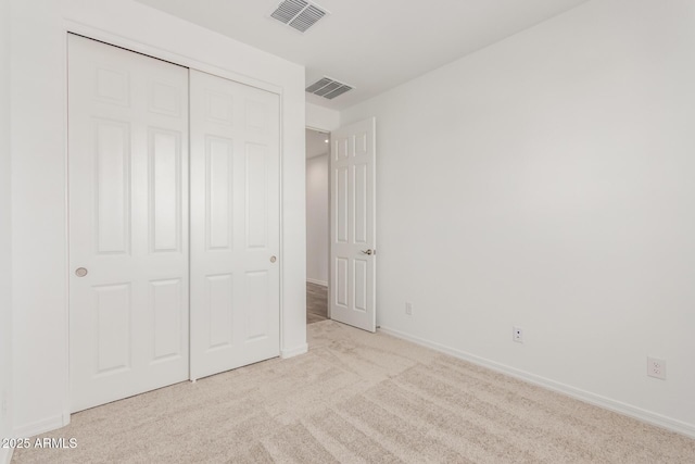 unfurnished bedroom featuring light carpet and a closet