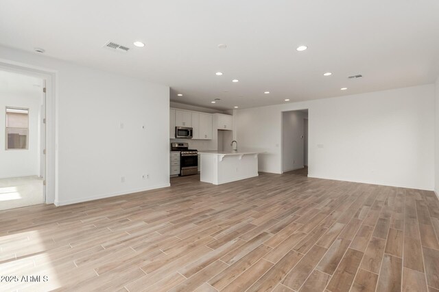 unfurnished living room featuring light wood-type flooring and sink