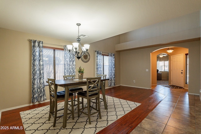 dining space featuring dark wood-type flooring and ceiling fan with notable chandelier