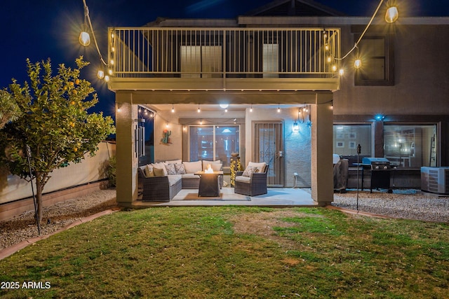 back house at twilight featuring a yard, an outdoor hangout area, and a balcony