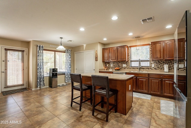 kitchen featuring a wealth of natural light, sink, a kitchen island, and pendant lighting