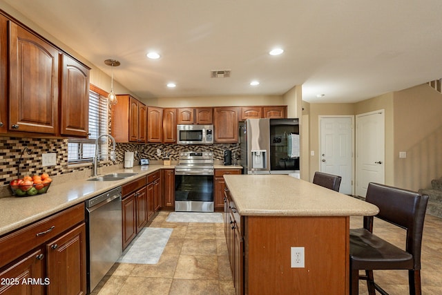 kitchen featuring a center island, sink, a breakfast bar area, decorative light fixtures, and stainless steel appliances