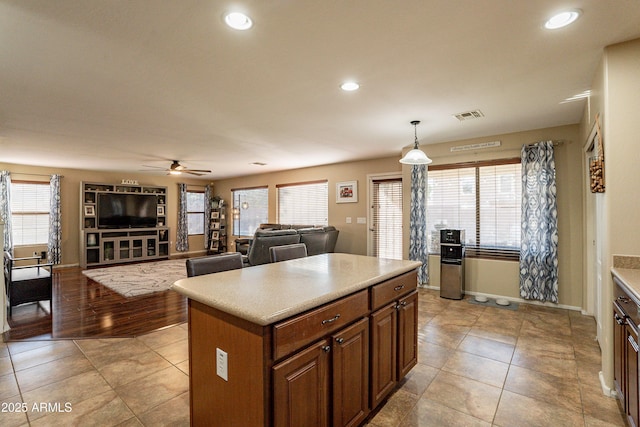 kitchen with pendant lighting, ceiling fan, a kitchen island, and a wealth of natural light