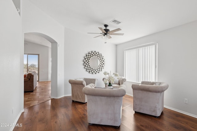 living area with arched walkways, a ceiling fan, wood finished floors, and baseboards