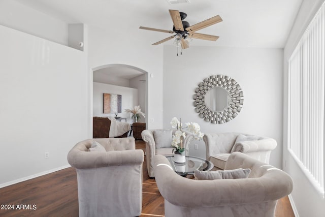 living area featuring arched walkways, a ceiling fan, baseboards, and dark wood-style flooring